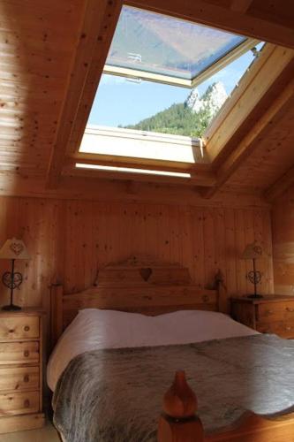 une chambre avec un lit avec une grande fenêtre dans l'établissement Chalet traditionnel Alpes, à Bernex