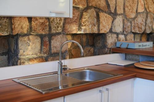 a kitchen with a sink and a stone wall at Villa Ariel in Luštica