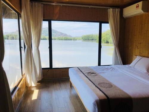 een slaapkamer met een bed en uitzicht op een meer bij gayang friendly water house homestay in Kota Kinabalu