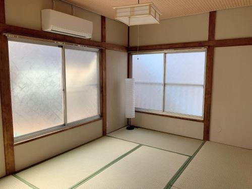 an empty room with two windows and a fan at Vivian house in Tokyo