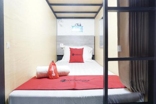 a bedroom with a bunk bed with a red blanket at RedDoorz Hostel @ Borobudur Street in Blimbing
