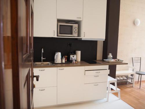 a kitchen with white cabinets and a microwave at Liza's Suite's - Room's with a View in Sala Comacina