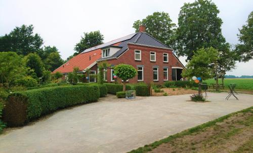 a large red house with a driveway in front of it at Appartementen BuitenWedde Westerwolde in Wedde