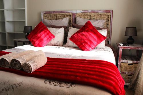 een bed met rode en witte kussens erop bij African Adventures Accommodation in Joostenberg Vlakte