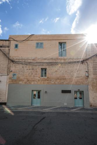 a brick building with two garage doors and the sun at Talbot & Bons Bed & Breakfast in Gudja