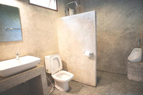 a bathroom with a white toilet and a sink at Suan Sook Homestay in Chom Thong