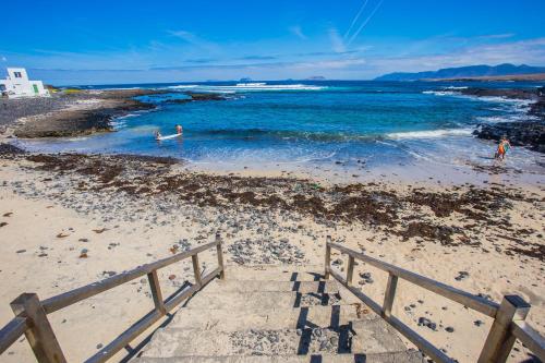 uma escada que leva à praia com pessoas na água em OHANA House in Caleta de Caballo em Caleta de Caballo