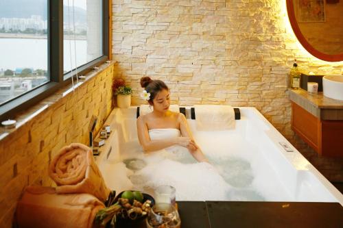 a woman is sitting in a bath tub at New Orient Hotel Da Nang in Da Nang