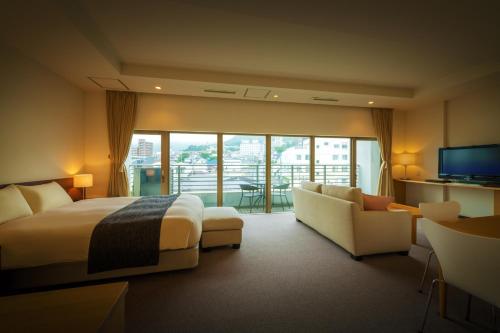 a hotel room with a bed and a couch and a television at Villa Concordia Resort & Spa in Hakodate