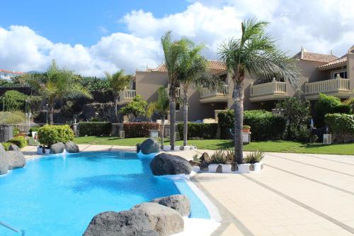 ein Swimmingpool vor einem Haus mit Palmen in der Unterkunft Residenz TraumBlick in Puerto de la Cruz