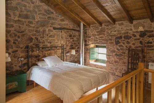 a bedroom with a bed in a stone wall at Villa Valedoso in Cabañas