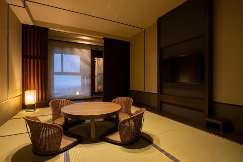 a room with a table and chairs and a television at Niseko Prince Hotel Hirafutei in Kutchan
