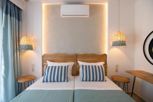 a bedroom with a bed with two blue and white pillows at Varkotopi Villas in Agios Pavlos