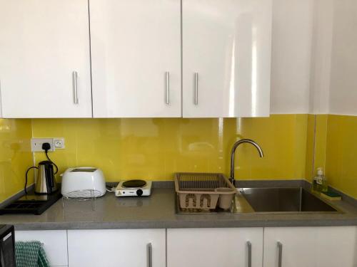 a kitchen with white cabinets and a sink at Sacha Tourist Residence 2 in Mahébourg