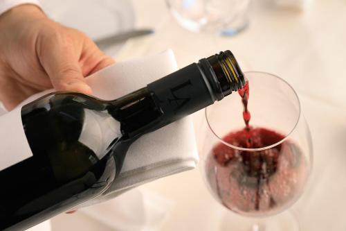 a person pouring red wine into a glass at Hotel Bellevue Wien in Vienna