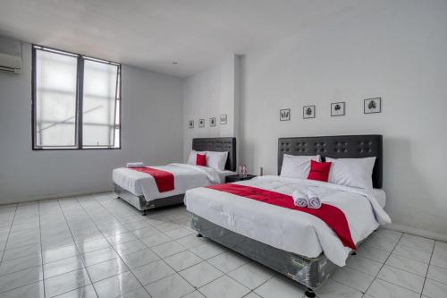 a bedroom with two beds with red and white sheets at RedDoorz Plus near Jakarta Kota Station in Jakarta