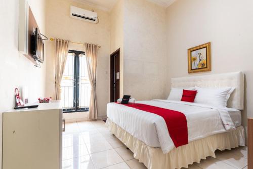 a bedroom with a large bed with a red blanket at RedDoorz @ Pengayoman Panakkukang 3 in Makassar