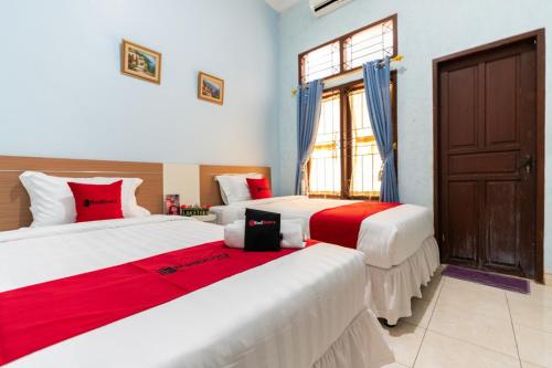 a bedroom with two beds with red and white at RedDoorz @ Pengayoman Panakkukang 3 in Makassar