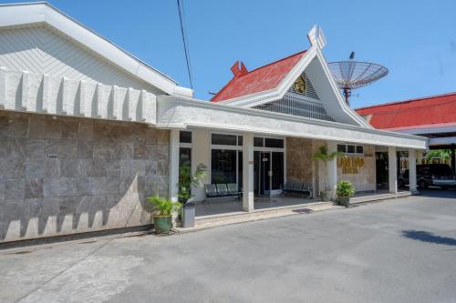 a building with a red roof and a stone wall at RedDoorz Plus Syariah at Alam Raya Hotel in Palu