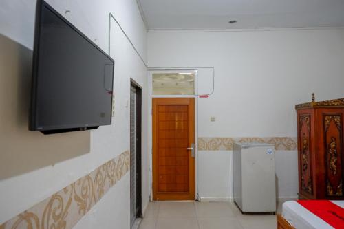 a room with a flat screen tv on a wall at RedDoorz Plus Syariah at Alam Raya Hotel in Palu