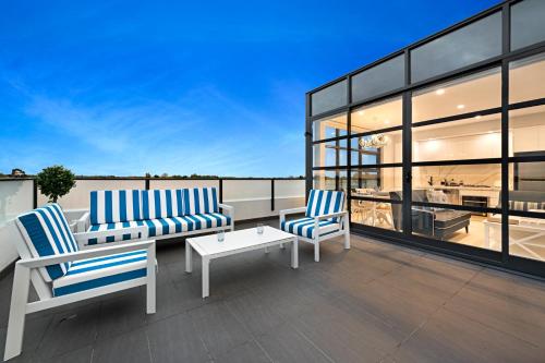 a patio with two chairs and a table on a roof at The Hamptons Apartments - St Kilda in Melbourne