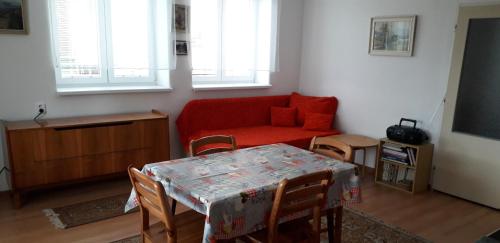 a living room with a table and a red couch at Apartmán Woodcock in Poniklá