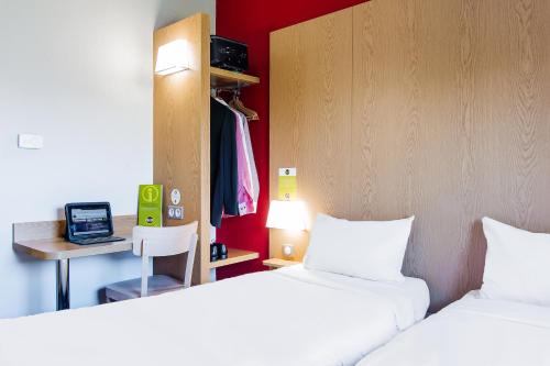 a room with two beds and a desk with a computer at B&B HOTEL Toulouse Purpan Zénith in Toulouse