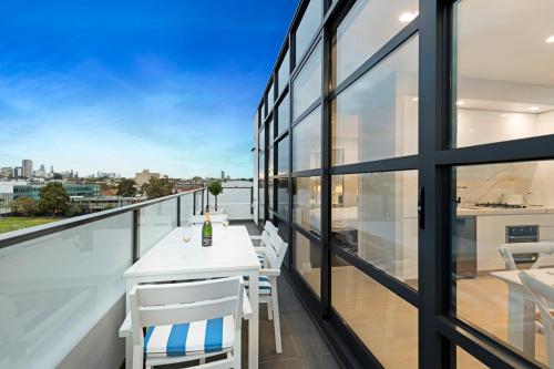a balcony with a white table and chairs at The Hamptons Apartments - St Kilda in Melbourne