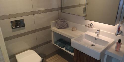 a bathroom with a sink and a toilet and a mirror at Pearls Sky 2102 Umhlanga in Durban