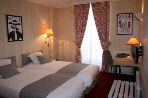 a hotel room with two beds and a desk at Hôtel Le D'Avaugour in Dinan