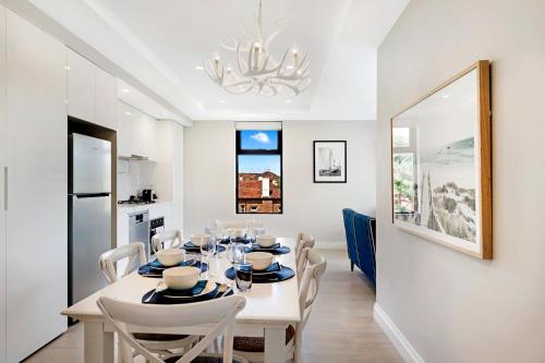 a dining room with a white table and chairs at The Hamptons Apartments - St Kilda in Melbourne