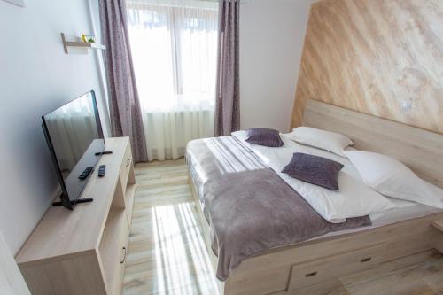 a bedroom with a large bed with a wooden headboard at Apartamente Primaverii in Buşteni