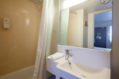 a bathroom with a sink and a mirror and a shower at B&B HOTEL Troyes Barberey in Barberey-Saint-Sulpice