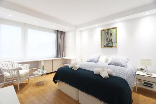 a bedroom with a bed and a chair and windows at Urbantec Realty - Plaza de Colón in Madrid