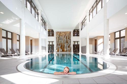 a woman laying in a pool in a building at Grand Hotel des Bains Kempinski in St. Moritz