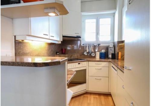 a kitchen with white cabinets and a wooden floor at The Swiss Paradise 1 Penthouse apartment in Wirzweli
