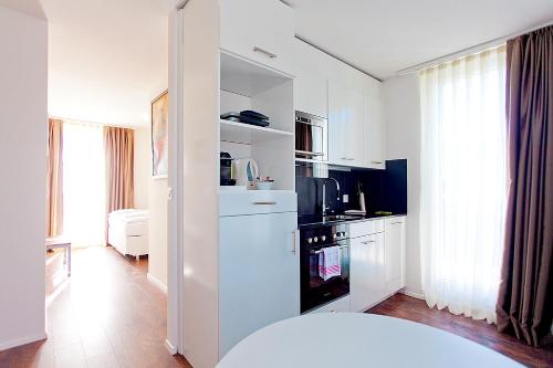 a kitchen with white cabinets and a black appliance at Suite Apartments by Livingdowntown in Zurich