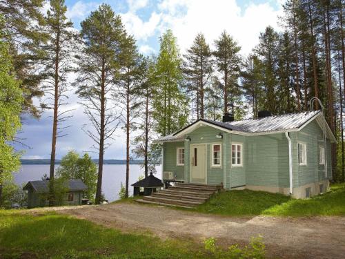 a small green house on the side of a lake at Holiday Home Tuuliranta by Interhome in Nurmes