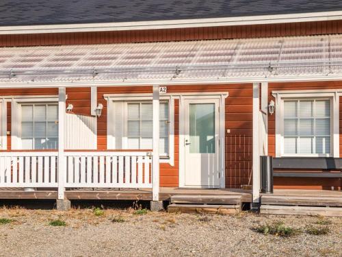 ein Holzhaus mit einer weißen Tür und Fenstern in der Unterkunft Holiday Home Karitahko a 3 by Interhome in Tahkovuori