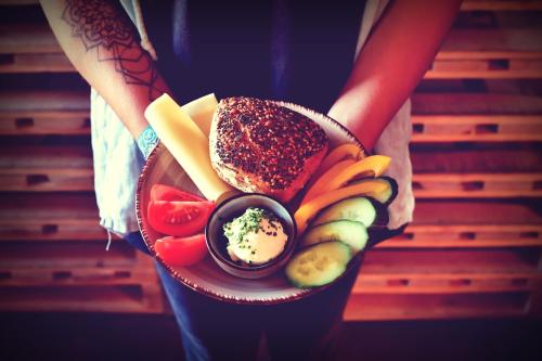 a person holding a plate of food with cheese and vegetables at Melbo's Home in Lindau