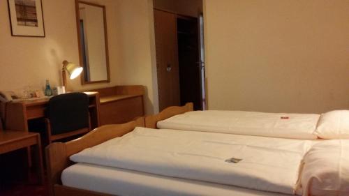 a hotel room with a bed, desk, and mirror at Hotel Garni Stadt Friedberg in Friedberg