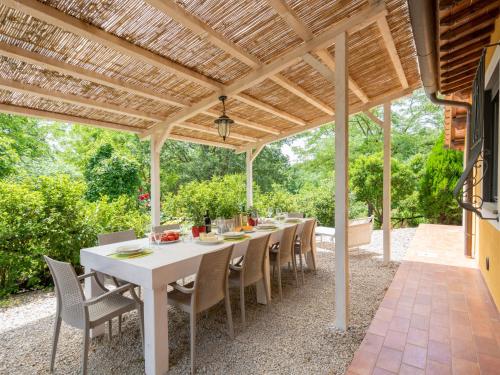 a white table and chairs under a wooden pergola at Holiday Home Villa Lavinia by Interhome in Montevarchi
