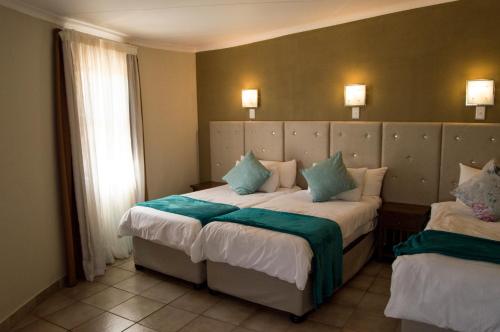 a hotel room with two beds with green and white pillows at Crystal Rose Lodge & Spa in Krugersdorp