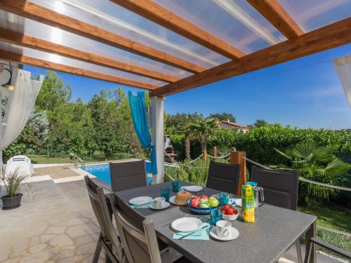 taras ze stołem i krzesłami oraz basenem w obiekcie Holiday Home Villa Joy by Interhome w mieście Novigrad