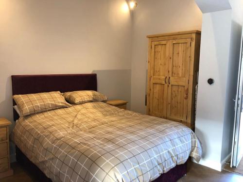 een slaapkamer met een bed en een houten kast bij The Dairy, Wolds Way Holiday Cottages, 1 bed studio in Cottingham