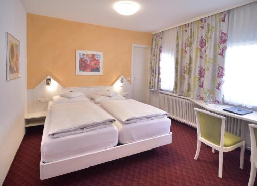 a hotel room with two beds and a desk at Hotel - Restaurant Hirsch in Heimsheim