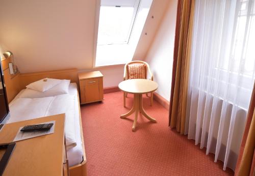 a hotel room with a bed and a chair and a window at Hotel - Restaurant Hirsch in Heimsheim