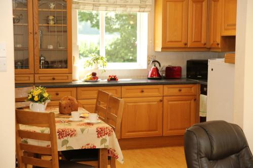 a kitchen with a table and a white refrigerator at Pheasant Walk at Eaton Manor in Church Stretton