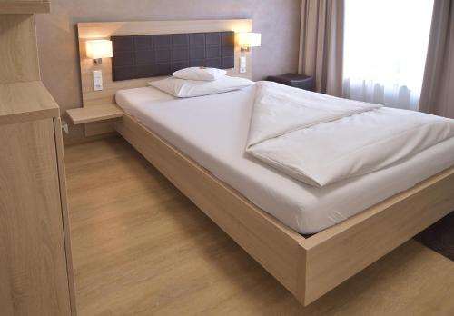 a large white bed in a small room at Hotel - Restaurant Hirsch in Heimsheim