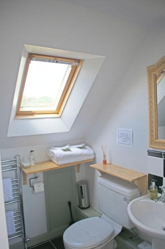 a bathroom with a toilet and a sink and a window at Innisfree Cottage in Eyam